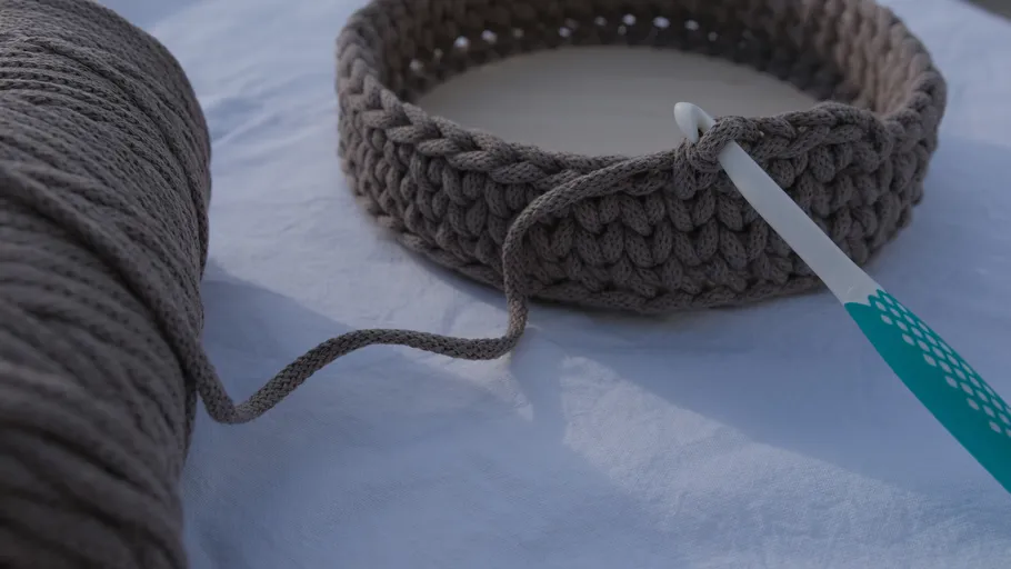 Crochet basket in progress with hook.