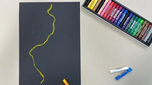 Colorful pastels on table, black paper drawing.