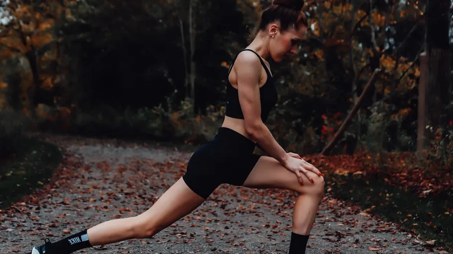 Woman stretching in park during autumn.