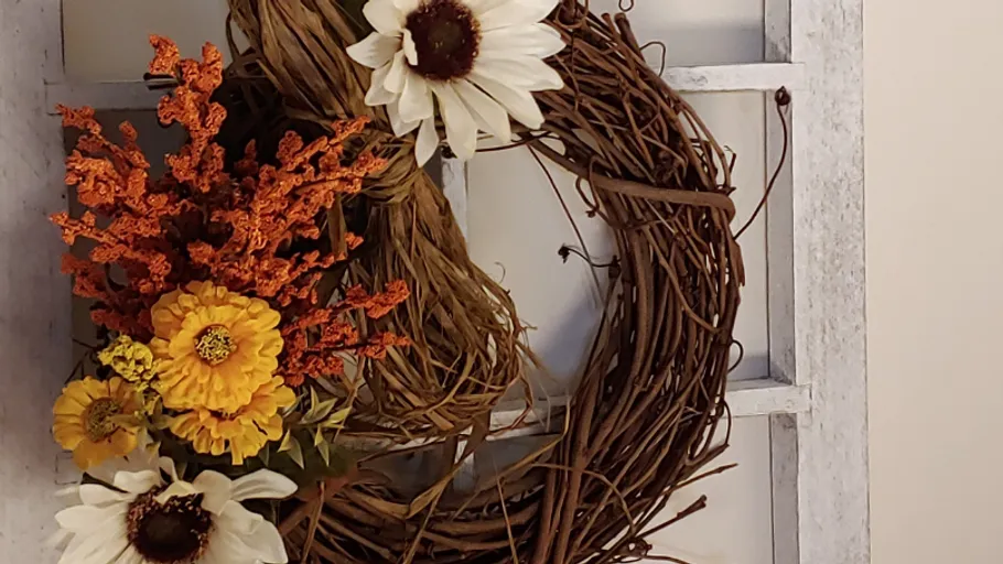 Floral wreath hanging on rustic window frame.