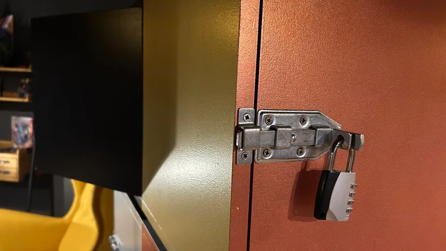 Padlock on metal cabinet in room corner.