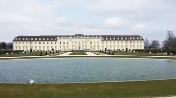 Large palace with pond, surrounded by gardens.