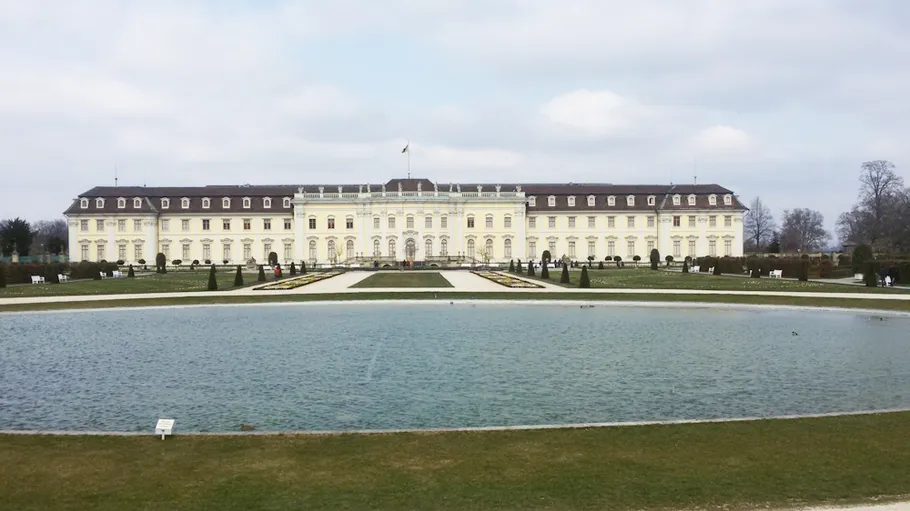 Großes Schloss mit Teich, umgeben von Gärten.