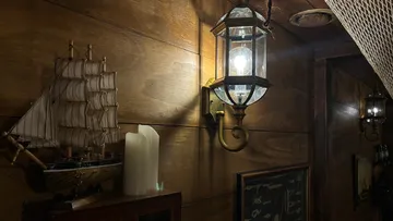 Model ship, lantern on wooden wall.