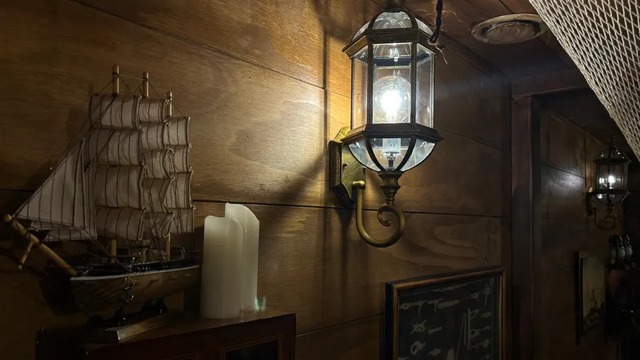 Model ship, lantern on wooden wall.