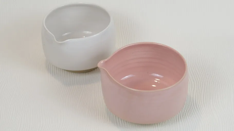 Rosa und weiße Keramikschalen auf Tisch.
