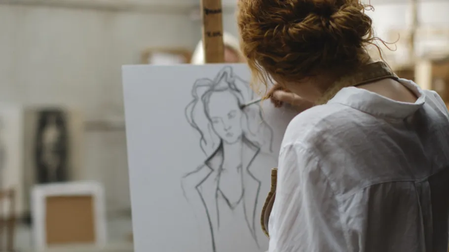Artist sketching on canvas in studio.