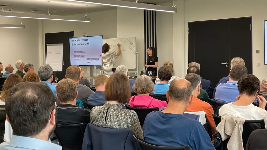 Redner präsentiert vor Publikum im Konferenzraum.