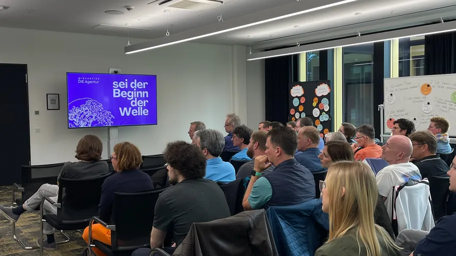 Personen im Konferenzraum schauen Präsentation.