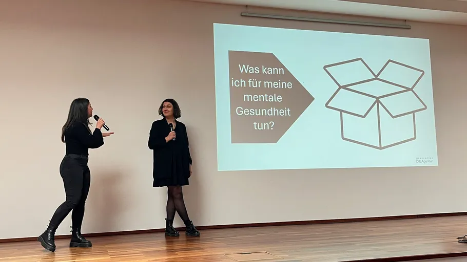 Zwei Frauen präsentieren vor einer Leinwand.