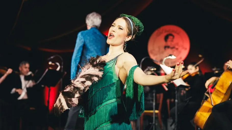Singer in green dress performing on stage.
