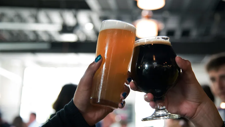 Two people clinking beer glasses indoors.