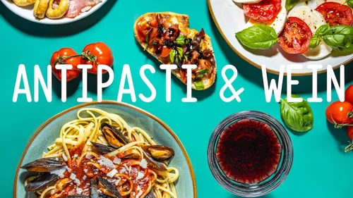 Pasta, wine, and appetizers on turquoise table.
