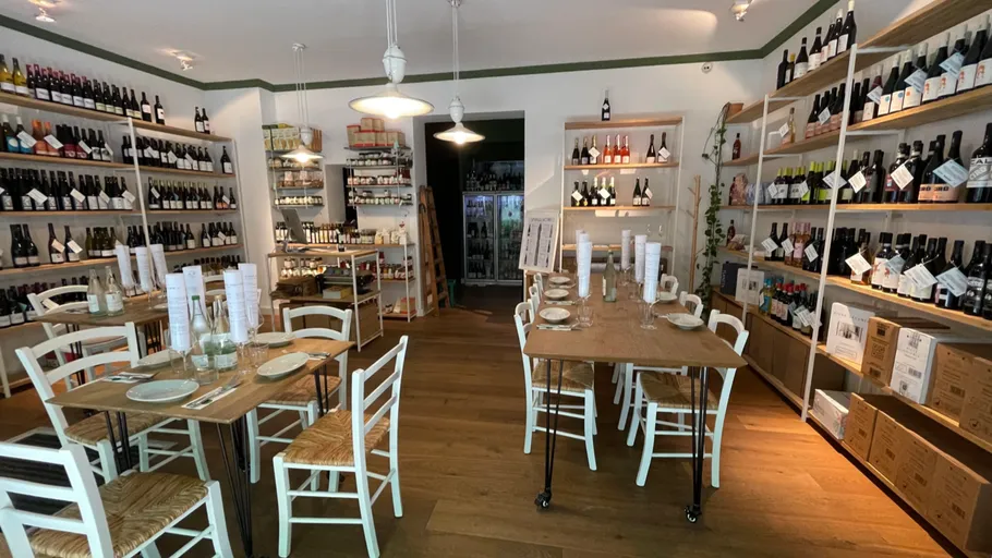 Wine shop with tables and shelves of wine.