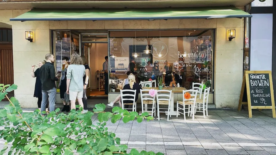 People gathering outside a cafe on a street.