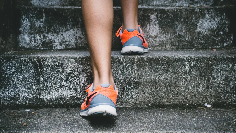 Person climbing stone stairs wearing orange sneakers.