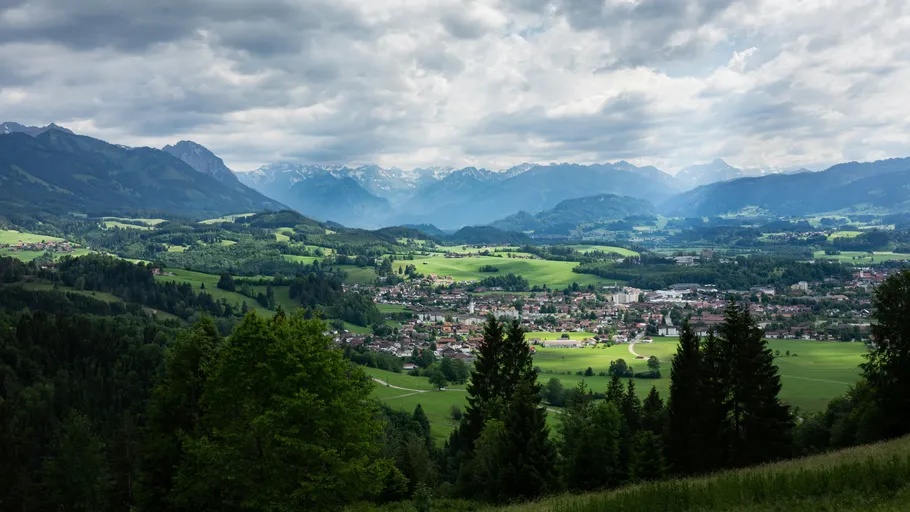 Mountain village with forests and cloudy sky.