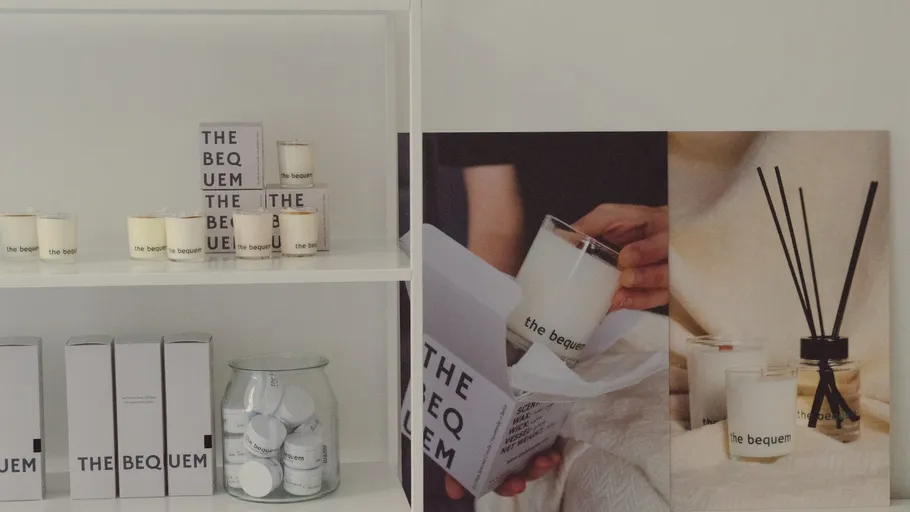 Candles and reed diffusers on white shelves.