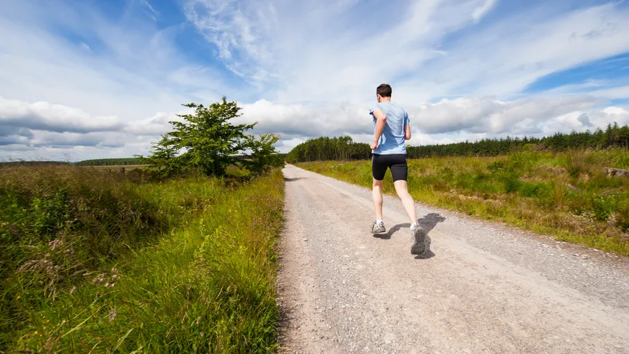 Man running on rural gravel path.