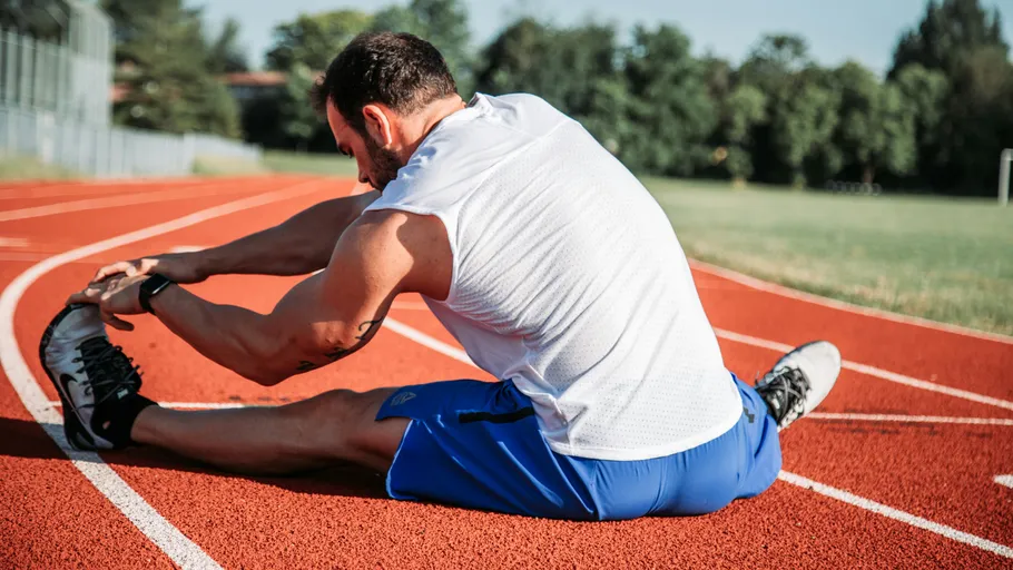 Mann dehnt sich auf running track im Freien.