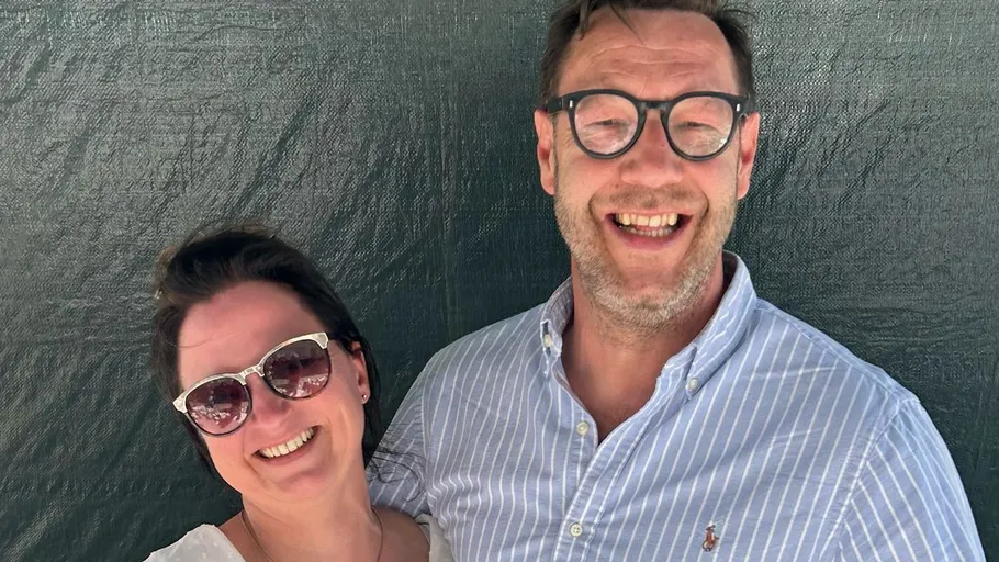 Smiling couple wearing glasses, outdoor setting.