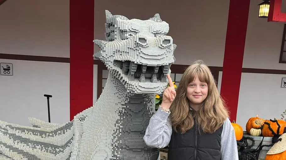 Person standing next to a dragon sculpture outside.