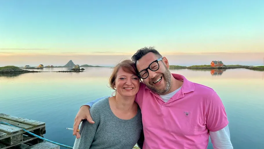 Smiling couple hugging by a calm lake.