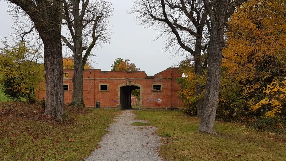 Brick building with archway, surrounded by trees.
