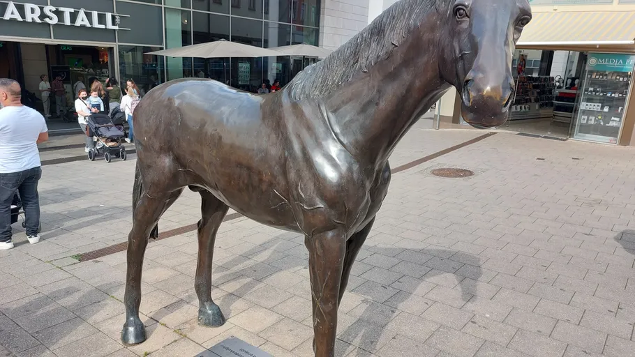 Bronze horse statue on city street.