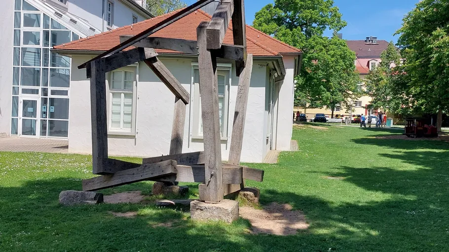Wooden sculpture on grassy lawn near building.