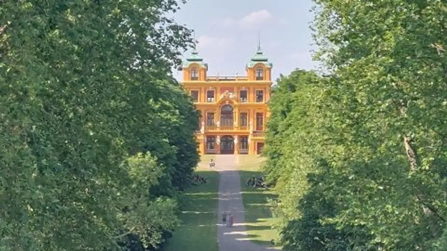 Yellow building with pathway, surrounded by trees.