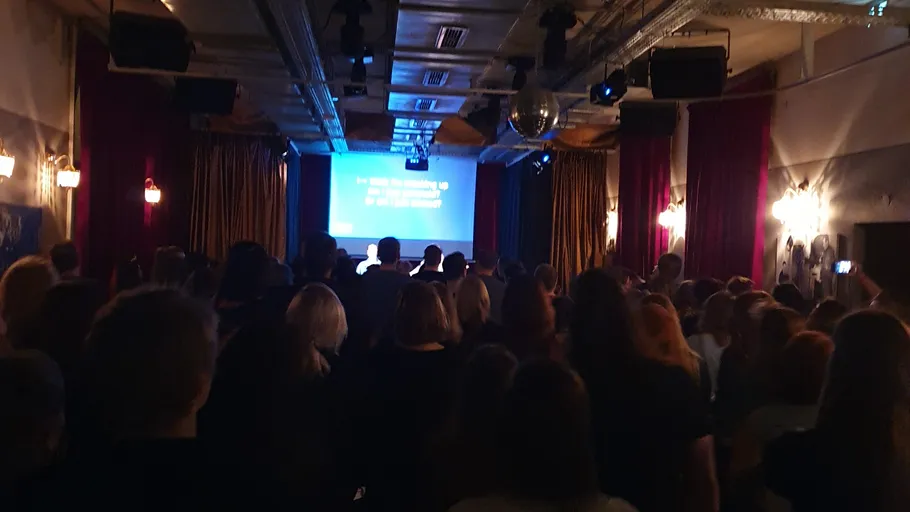 Audience watching screen in dimly lit room.