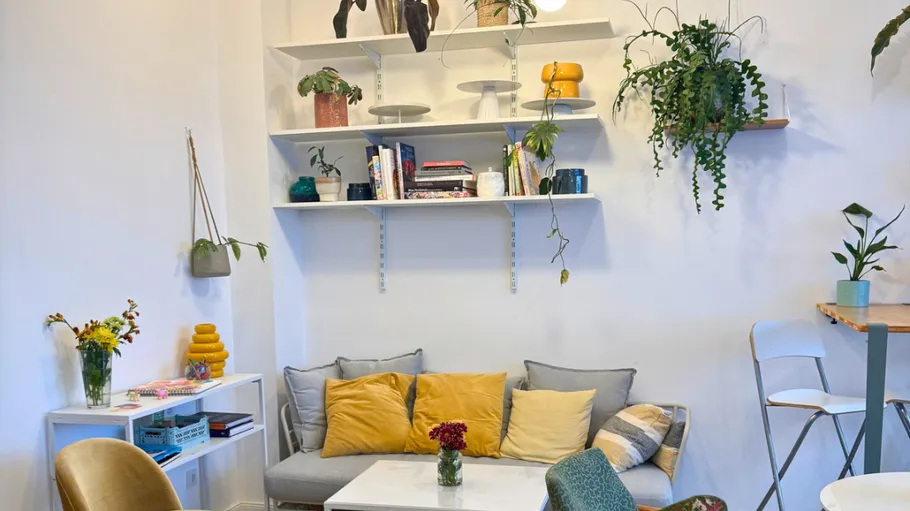 Gemütliches Wohnzimmer mit Pflanzen und Kissen.
