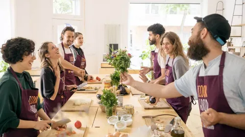 Group cooking class, participants chopping vegetables happily.