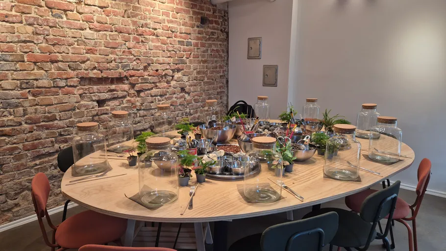 Table with jars and plants in brick-walled room.