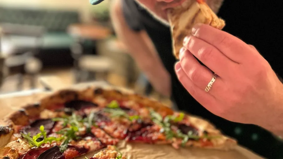 Person eating slice of pizza in restaurant.