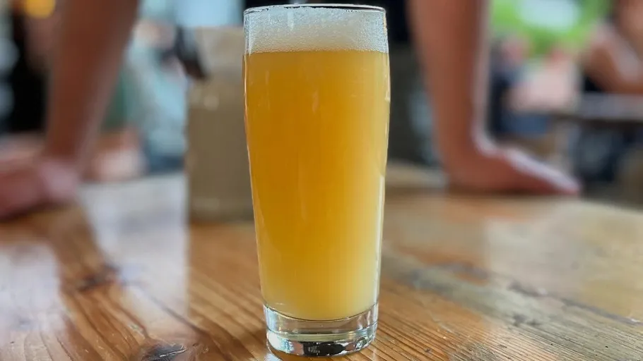 Tall glass of beer on wooden table.