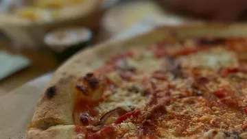 Nahaufnahme eines Käsestück einer Pizza.