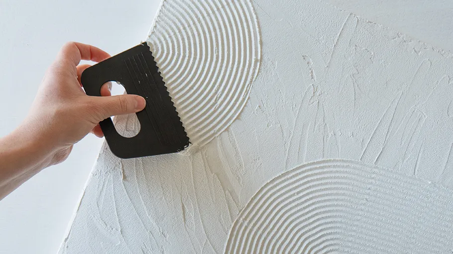 Hand using tool to texture wall.