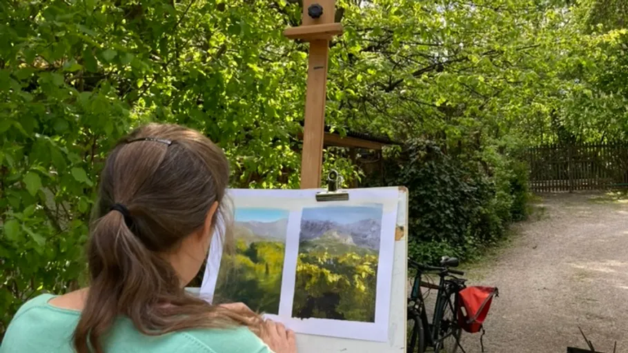 Person malt Landschaft im Freien neben einem Fahrrad.