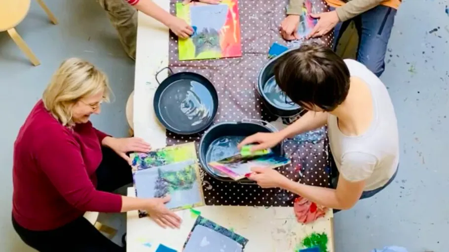 People creating art with colorful papers indoors.
