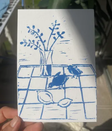 Blue illustration of vase, birds, lemons on table.