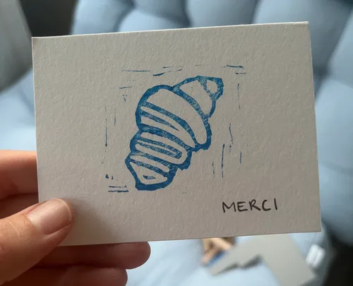 Karte mit blauem Croissant-Design, Text 'MERCI'.