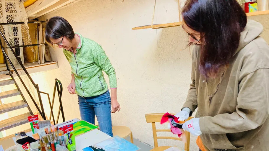 Two women painting in a small studio.