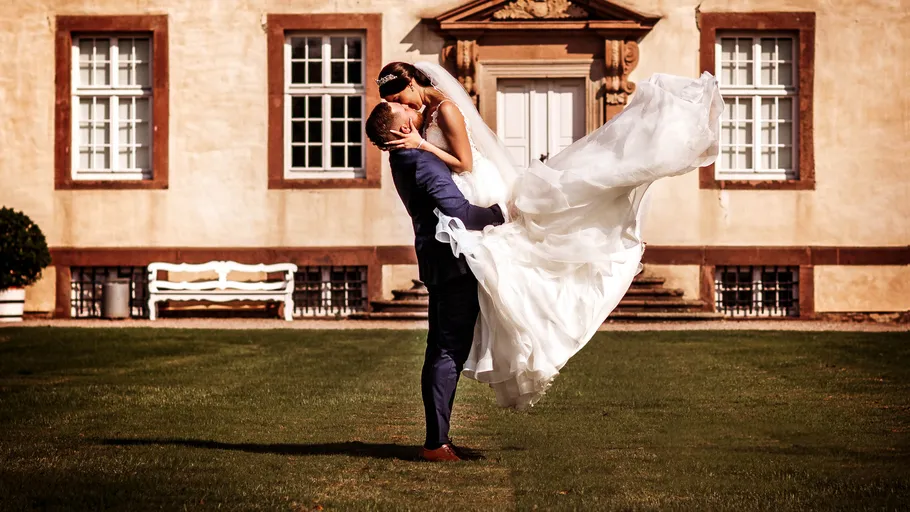 Bride and groom embracing outside elegant building.