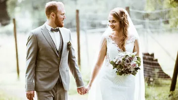 Bride and groom holding hands outdoors.