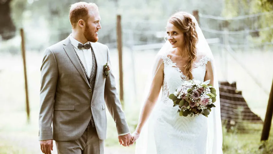Bride and groom holding hands outdoors.