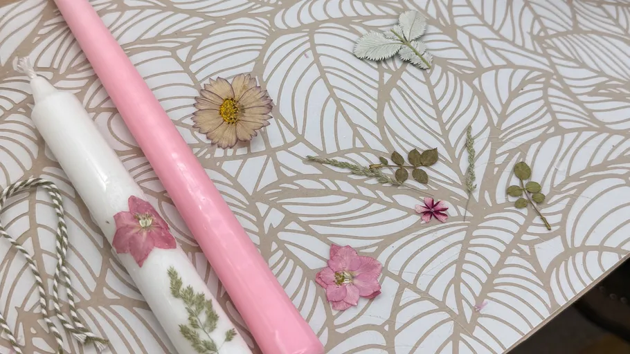 Rosa und weiße Kerzen auf gemustertem Papier.