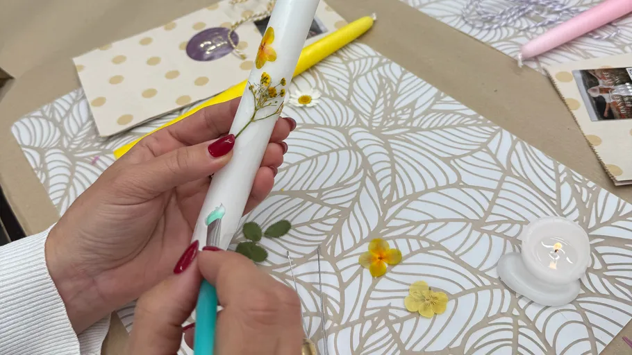 Hand decorating candle with pressed flowers.