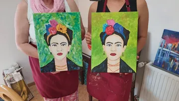 Zwei Frauen halten ähnliche Frida Kahlo Gemälde.